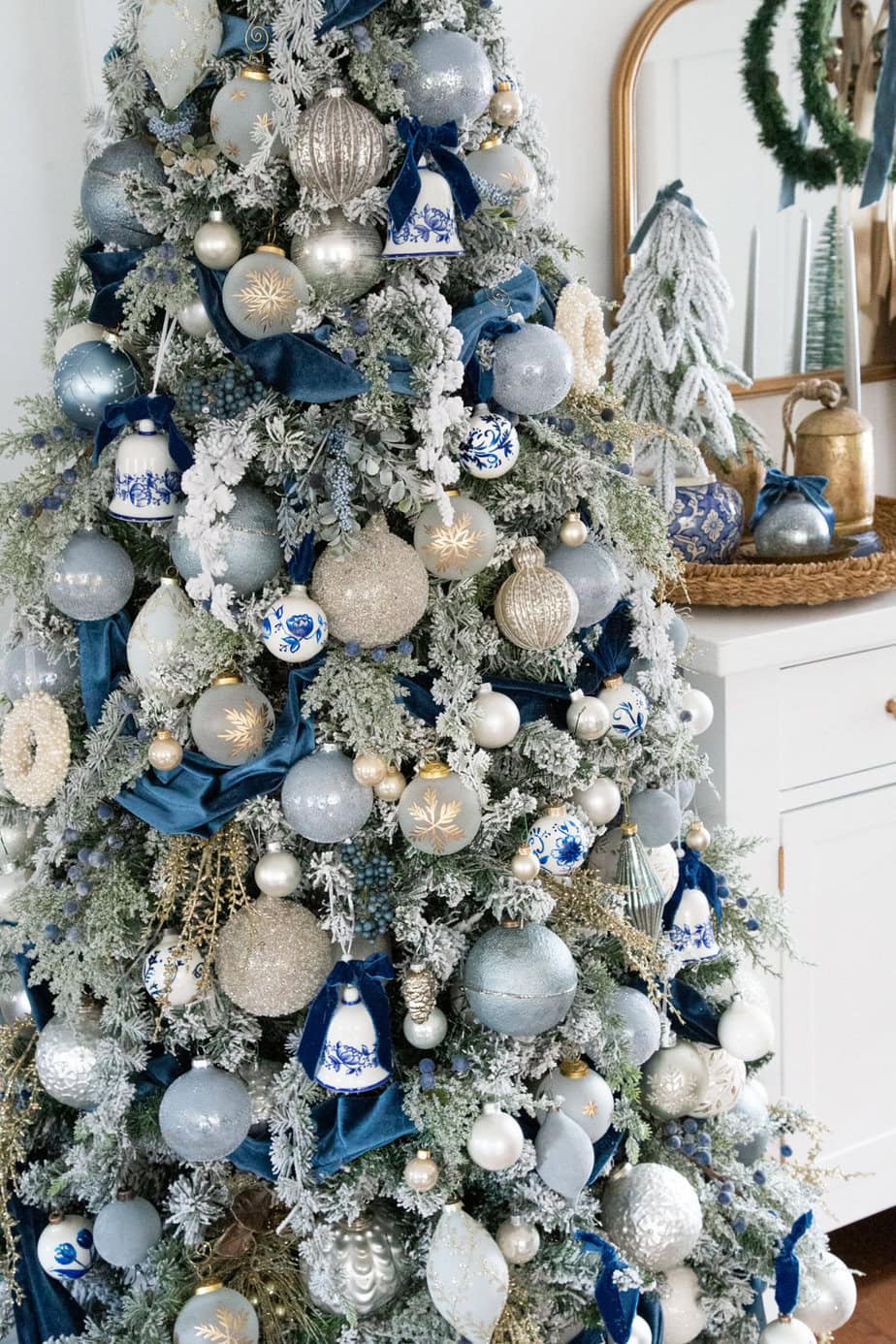 A blue-and-white Christmas tree with velvet ribbons, porcelain ornaments and champagne accents